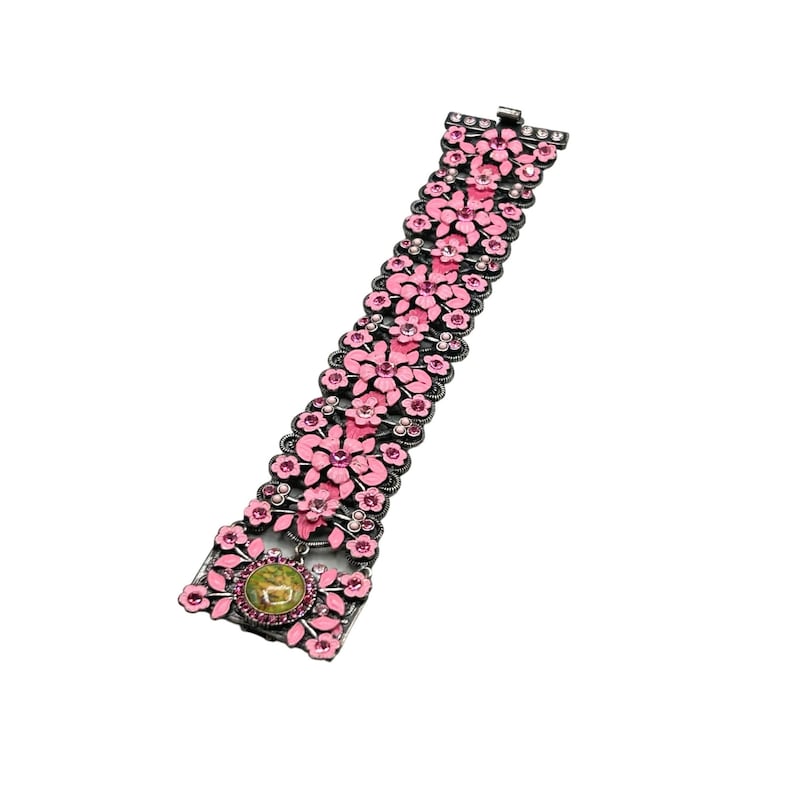 May include: A pink and silver floral bracelet with a large, round, green and gold cameo in the center.