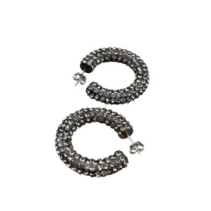 May include: A pair of silver-toned hoop earrings. Each earring is encrusted with small, clear crystals, giving them a sparkling appearance. The earrings have a post-and-clutch closure.