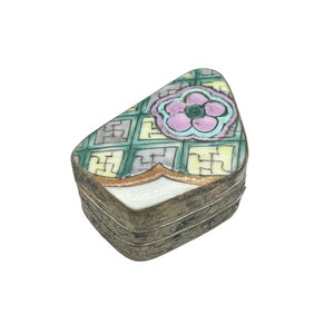 May include: A small, silver, rectangular box with a hinged lid. The lid is decorated with a green, yellow, and pink floral pattern. The box is about 2 inches long and 1 inch wide.