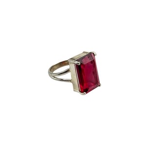 May include: A silver ring with a large, rectangular, dark red gemstone.