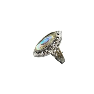 May include: A silver ring with an oval-shaped abalone shell inlay. The ring has a delicate filigree design.