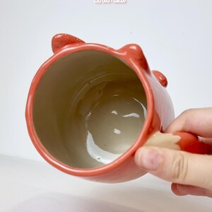 K&ouml;nnte beinhalten: Rote Keramik-Tasse in Fuchsform, mit Ohren und einem Schwanz als Griff. Das Innere ist hellbeige. Auf der Tasse steht "Ceramiku" und "ceramikushop.etsy.com".