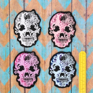 May include: Four embroidered skull patches with intricate lace designs. The skulls are white, pink, and black with white lace details. The patches are approximately 3 inches in diameter.