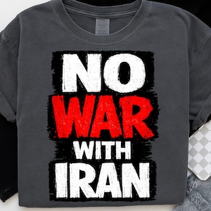 May include: Dark gray t-shirt with the words "NO WAR WITH IRAN" in a distressed, bold font. The text is arranged in three lines, with "NO" and "WITH IRAN" in white and "WAR" in red.