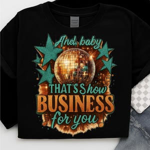 Peut inclure: Sweat-shirt noir à col rond avec un motif graphique. Le motif présente une boule disco, des étoiles turquoise et le texte "And baby, that's how business for you" en orange et turquoise.
