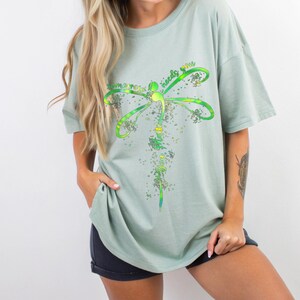 May include: A light green t-shirt with a dragonfly graphic and the text "Sometimes the world needs you".