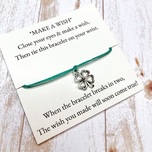 May include: A green string bracelet with a silver four-leaf clover charm. The card attached reads "*MAKE A WISH* Close your eyes & make a wish, Then tie this bracelet on your wrist. When the bracelet breaks in two, The wish you made will soon come true!"