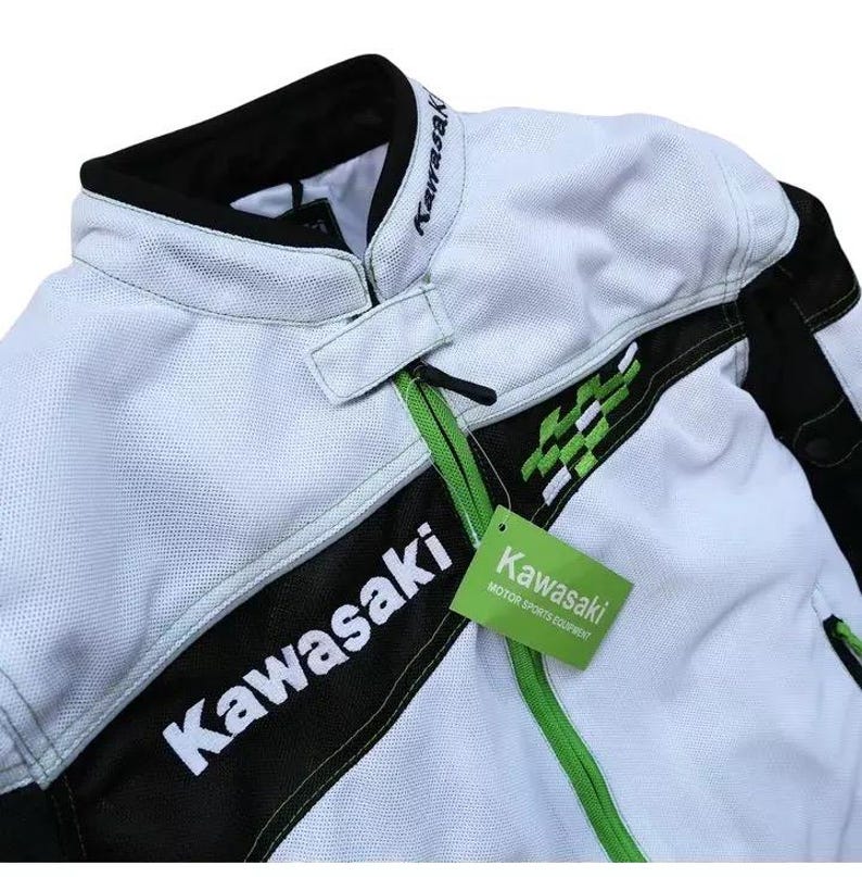 May include: White and black motorcycle jacket with green accents. The jacket has the word "Kawasaki" written on the front in black and white lettering. A green tag with the word "Kawasaki" and the text "Motor Sports Equipment" is attached to the jacket.