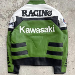 K&ouml;nnte beinhalten: Gr&uuml;ne und schwarze Rennjacke mit dem Wort "RACING" &uuml;ber den Schultern. Das Wort "Kawasaki" ist wei&szlig; auf dem R&uuml;cken aufgedruckt. Die Jacke hat wei&szlig;e und schwarze Akzente und einen kleinen Aufn&auml;her am &Auml;rmel.