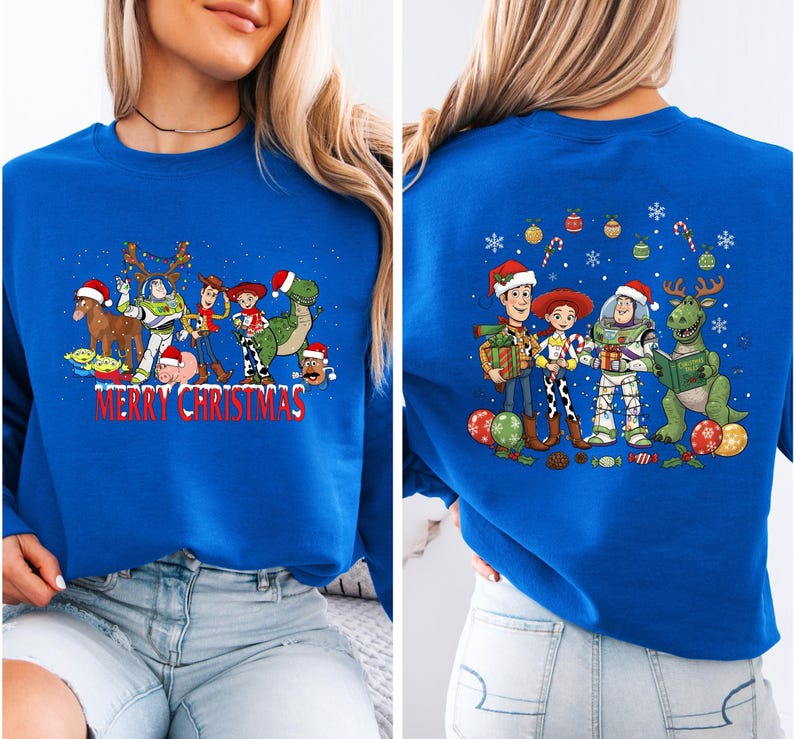 May include: Royal blue sweatshirt featuring a festive design with cartoon characters, including a dinosaur, a spaceman, and a cowboy, all wearing Santa hats. The front of the sweatshirt has the text "MERRY CHRISTMAS".