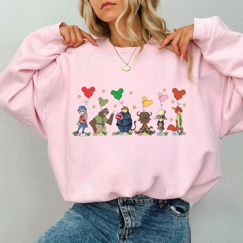 A woman wearing a pink sweatshirt with a cartoon character design on it.