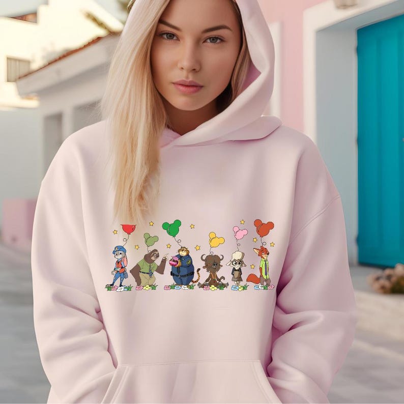 A young woman wearing a pink hoodie with a graphic of cartoon characters and hearts on it.