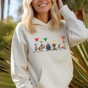 A woman wearing a white hoodie with a graphic of cartoon characters and hearts on it.