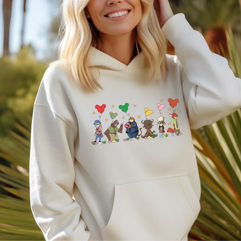 A woman wearing a white hoodie with a graphic of cartoon characters and hearts on it.