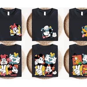 May include: Black t-shirts featuring Disney characters Minnie Mouse, Mickey Mouse, and Pluto. Each shirt has a colorful graphic of the character. The shirts are displayed on a woven surface.