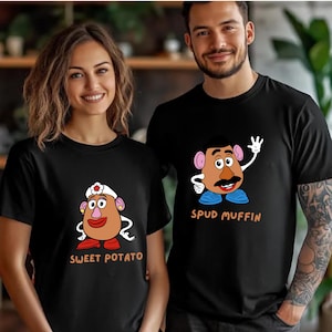 A smiling woman and a man wearing black t-shirts with cartoon characters printed on them.