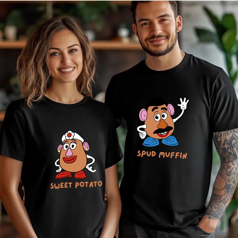 A smiling woman and a man wearing black t-shirts with cartoon characters printed on them.