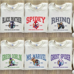 Puede incluir: Seis sudaderas de color crema con diferentes dise&ntilde;os de personajes de superh&eacute;roes. Cada sudadera presenta un personaje del universo Spider-Man, incluyendo Black Panther, Spidey, Rhino, Green Goblin, Ms. Marvel y Ghost Spider. El texto en cada sudadera dice "Spidey and his amazing friends" e incluye el a&ntilde;o "2021".