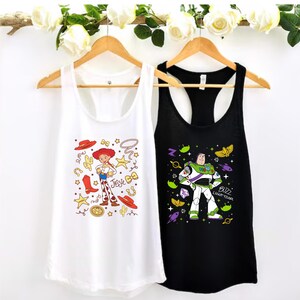 two tank tops hanging on a wooden hanger, each with a different design and character printed on them.