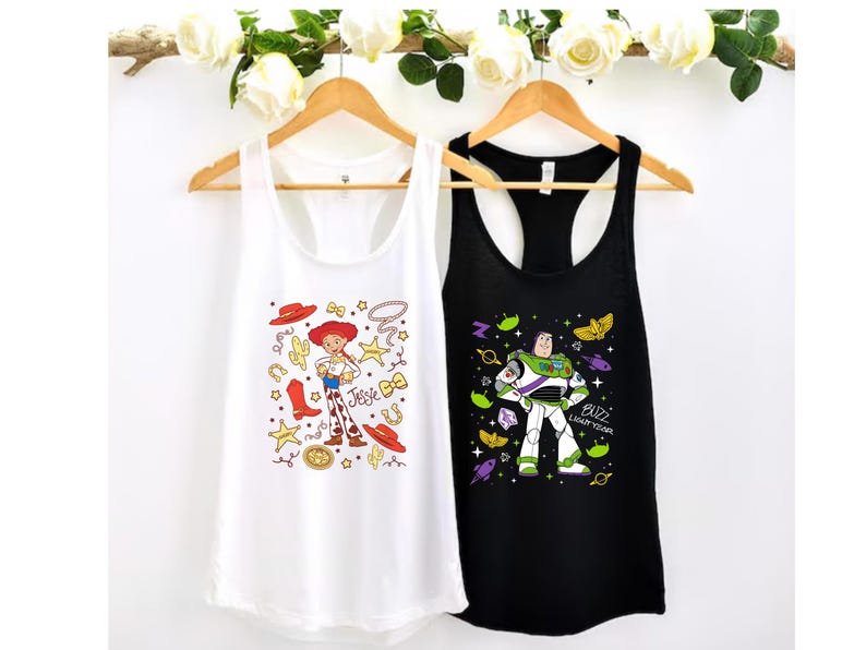 two tank tops hanging on a wooden hanger, each with a different design and character printed on them.