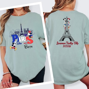 a woman wearing a grey t-shirt with a Paris-themed design, including the Eiffel Tower and Mickey Mouse.