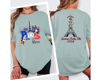 May include: A light green t-shirt featuring a graphic of the Eiffel Tower and the text "Paris Disneyland" with Mickey Mouse and Minnie Mouse. The back of the shirt has the Eiffel Tower with Disney characters and the text "Johnson Family Trip 2024".