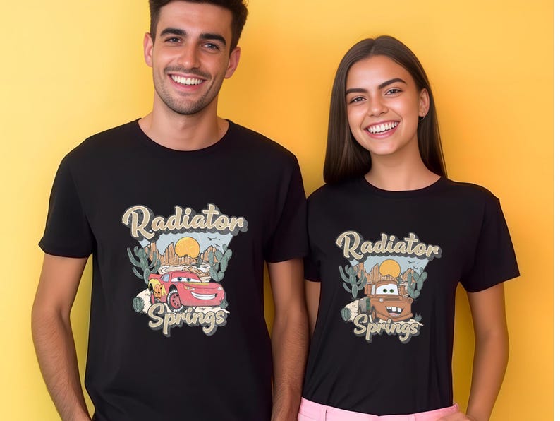 May include: Black t-shirts featuring a graphic of the Cars movie characters Lightning McQueen and Mater with the text "Radiator Springs". The design includes a desert landscape with cacti and a setting sun.
