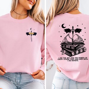 A woman wearing a pink long-sleeved shirt with a dragon design and a quote on the back.