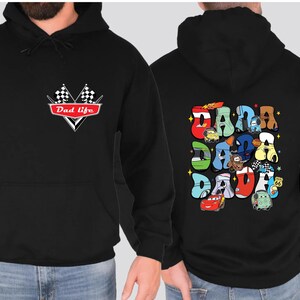 May include: Black hoodie with a red and white checkered flag design and the text "Dad Life" on the front. The back of the hoodie features a colorful graphic of cartoon cars spelling out "DADA" with stars.