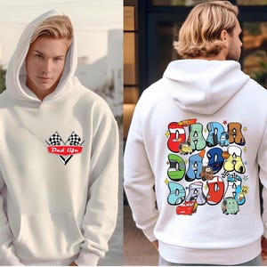 May include: White hooded sweatshirt with a red and black checkered flag design and the text "Dad Life" on the front. The back of the sweatshirt features a colorful graphic of the word "Dada" with cartoon cars and characters.