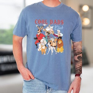 A man wearing a blue t-shirt with a graphic design of cartoon characters and text.