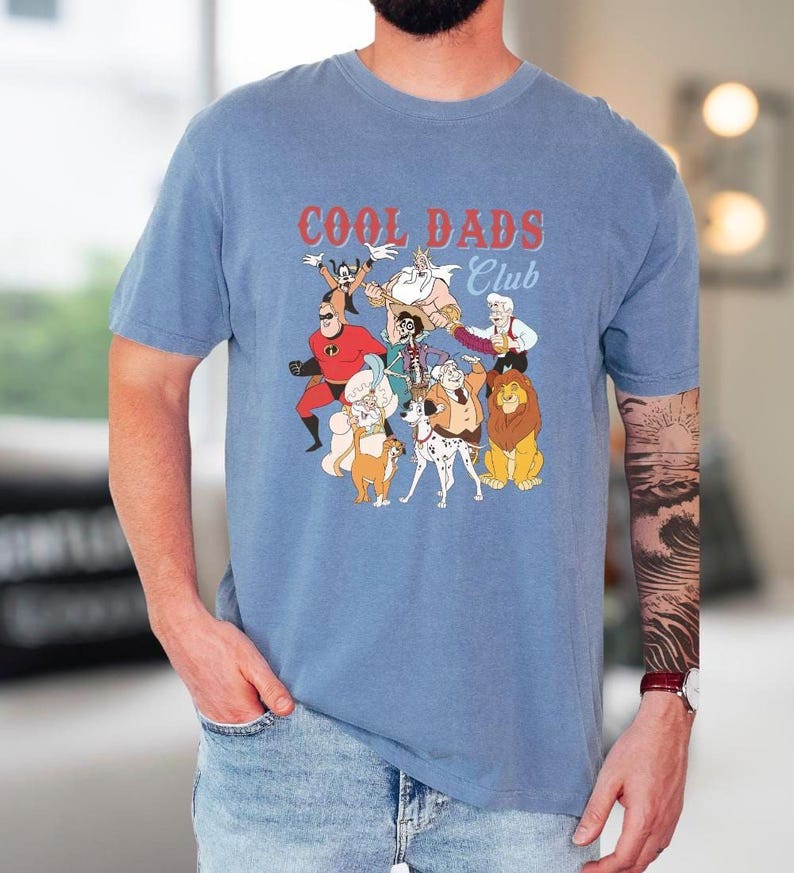 A man wearing a blue t-shirt with a graphic design of cartoon characters and text.