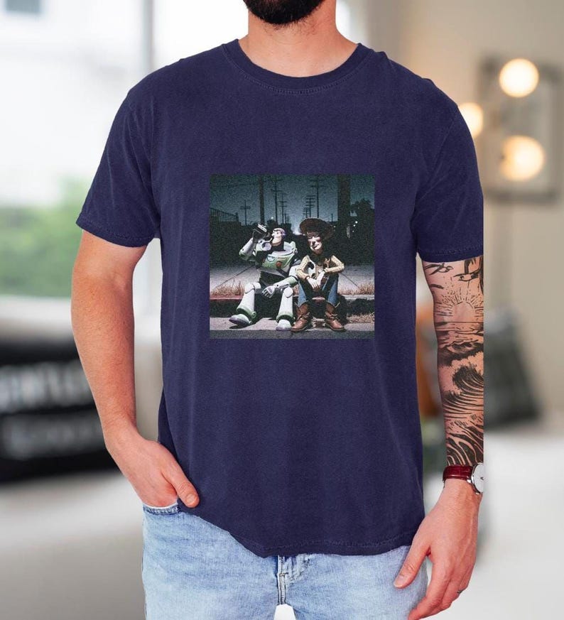 A man wearing a navy blue t-shirt with a graphic design featuring two people sitting on a bench.