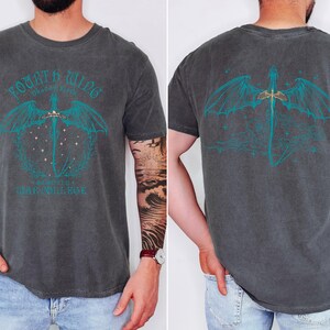 a man wearing a gray t-shirt with a graphic design on the back. The design features a dragon and a sword, along with the text "Fourth WILD" and "WILD COLLEGE".