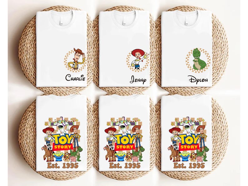 Puede incluir: Camisetas blancas con personajes de Toy Story. Algunas camisetas tienen nombres como "Charlie", "Jenny" y "Dylon". Otras camisetas muestran el logotipo de Toy Story y el texto "Est. 1995".