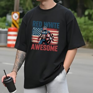 May include: A black short-sleeve t-shirt featuring a graphic print of Captain America in front of a distressed American flag. The text "RED WHITE" appears in blue above the character, and the word "AWESOME" is printed in red below the graphic.