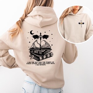 A woman wearing a beige hoodie with a graphic design on the back.