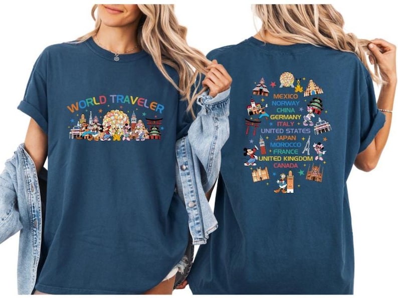 two women wearing blue t-shirts with colorful graphics and text on the back.