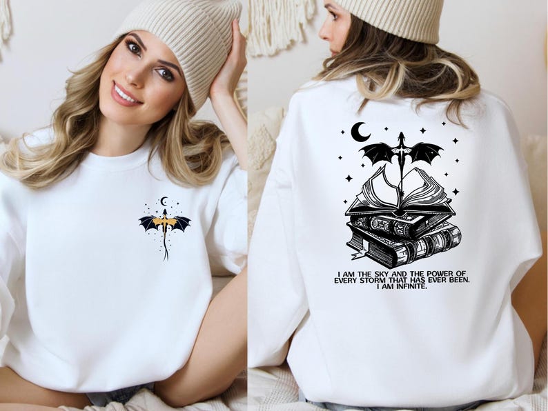 A woman wearing a white sweater with a graphic design on the back, including a bat, a book, and a crescent moon.