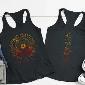 two black tank tops with different designs, laid out on a white background. There are also some jeans, a pair of sneakers, and a potted plant in the scene.