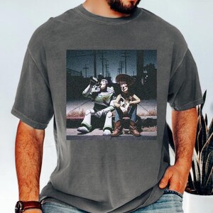 A man wearing a gray t-shirt with a graphic of two people sitting on a bench.