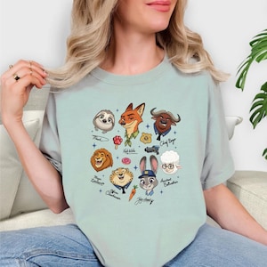 A woman wearing a light blue t-shirt with a graphic design featuring various cartoon animal characters.