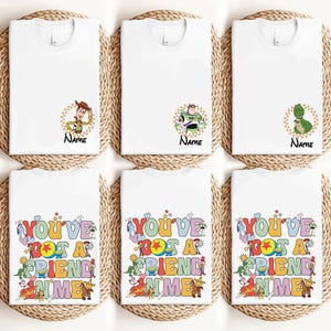 six white t-shirts with various cartoon character designs and text printed on them.