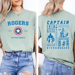 Puede incluir: Una camiseta verde claro con un logotipo de Capit&aacute;n Am&eacute;rica azul y rojo en la parte delantera y un gr&aacute;fico azul con el texto "Capit&aacute;n 1918 Steve Rogers" en la parte posterior.