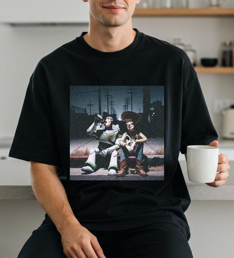 A person wearing a black t-shirt with a graphic of two characters from the Toy Story franchise, Buzz Lightyear and Woody, sitting together.