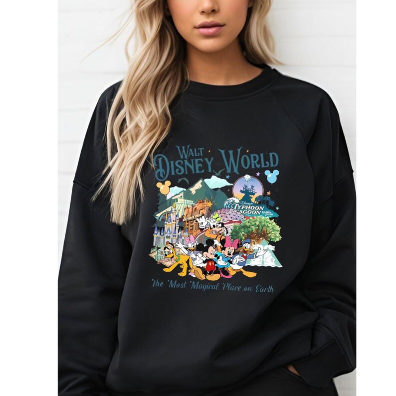 A woman wearing a black sweatshirt with a colorful graphic design featuring Disney characters and landmarks.