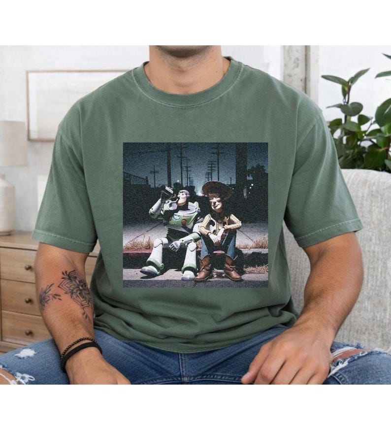 A person wearing a green t-shirt with a printed image of two people sitting on a bench.