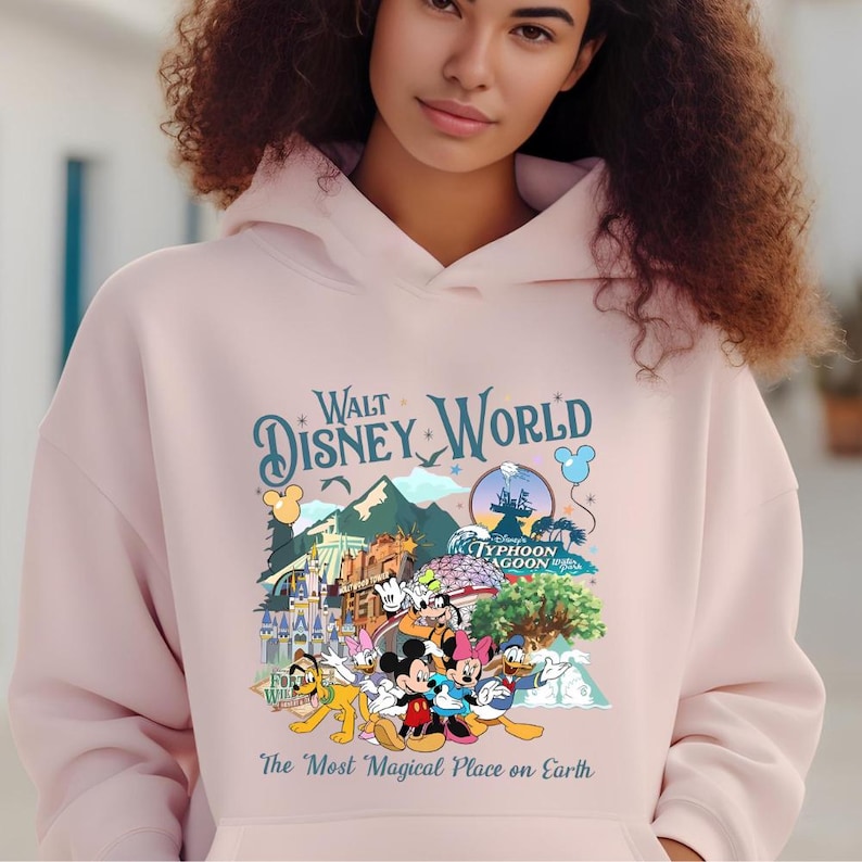 A woman wearing a pink hoodie with a Disney World-themed graphic printed on it.