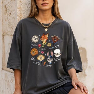 A woman wearing a gray t-shirt with a graphic design featuring various cartoon animal characters, including a sloth, lion, tiger, rabbit, and sheep.