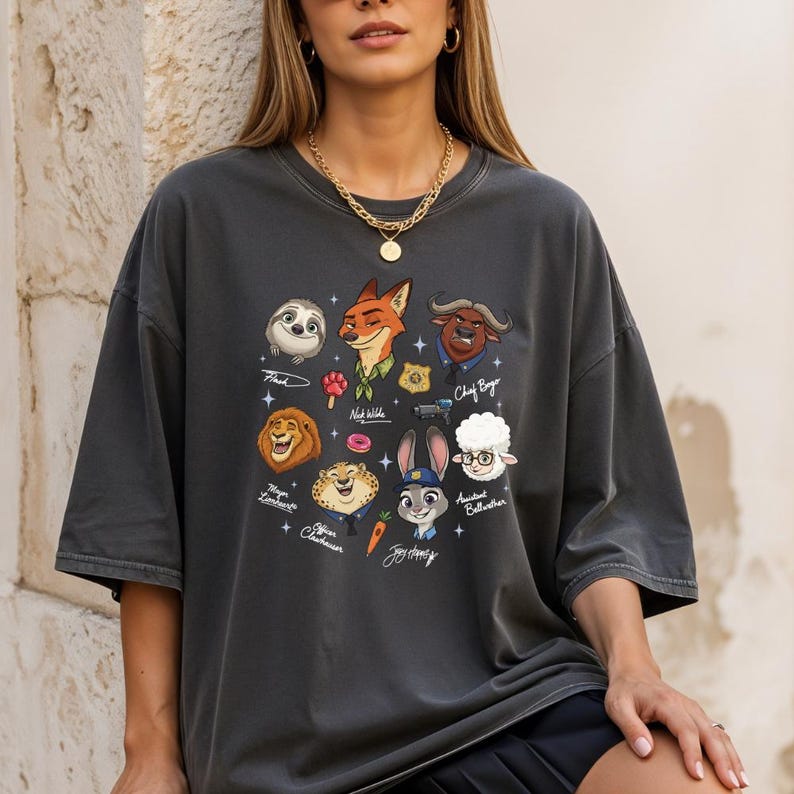 A woman wearing a gray t-shirt with a graphic design featuring various cartoon animal characters, including a sloth, lion, tiger, rabbit, and sheep.
